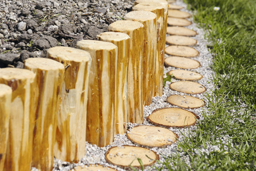 Holzstämme als Rasenkante